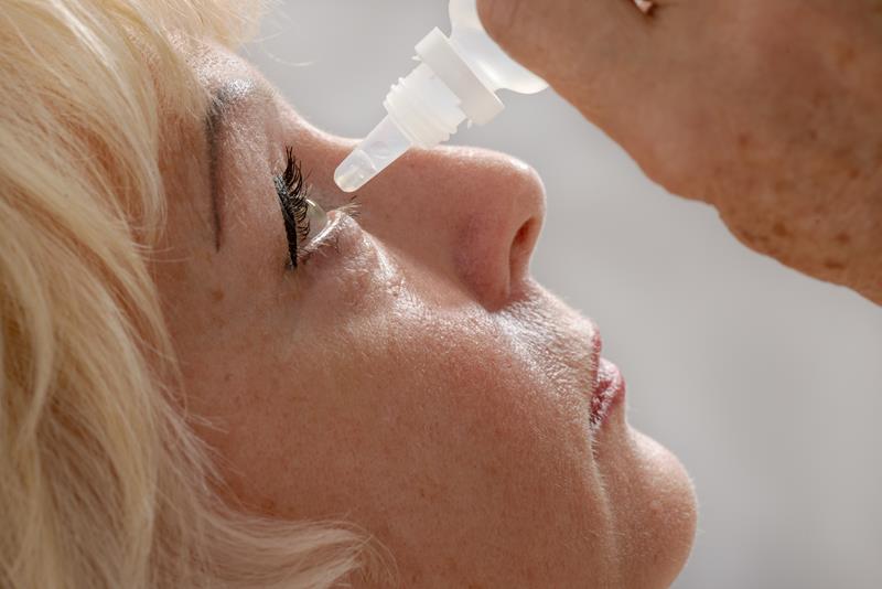Older person applying eye drops for dry eyes
